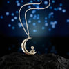 Silver crescent moon necklace with a fantail pendant on a dark surface with a blurred blue light background