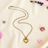 Gold heart-shaped necklace on a light background with decorative elements