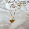 Gold butterfly necklace on a white fabric background