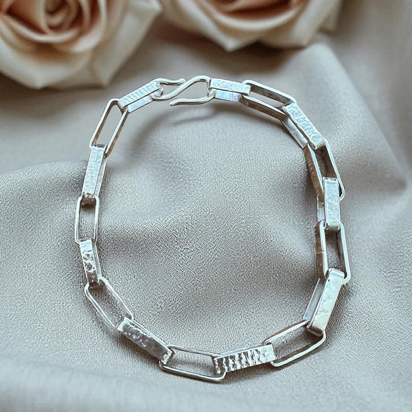 Silver bracelet on a beige fabric background with roses