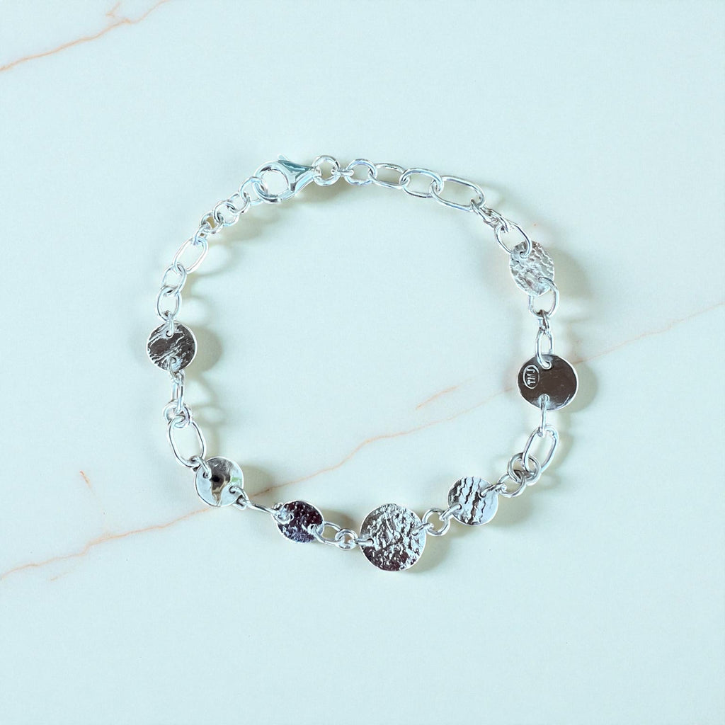 Silver bracelet with round discs on a light background