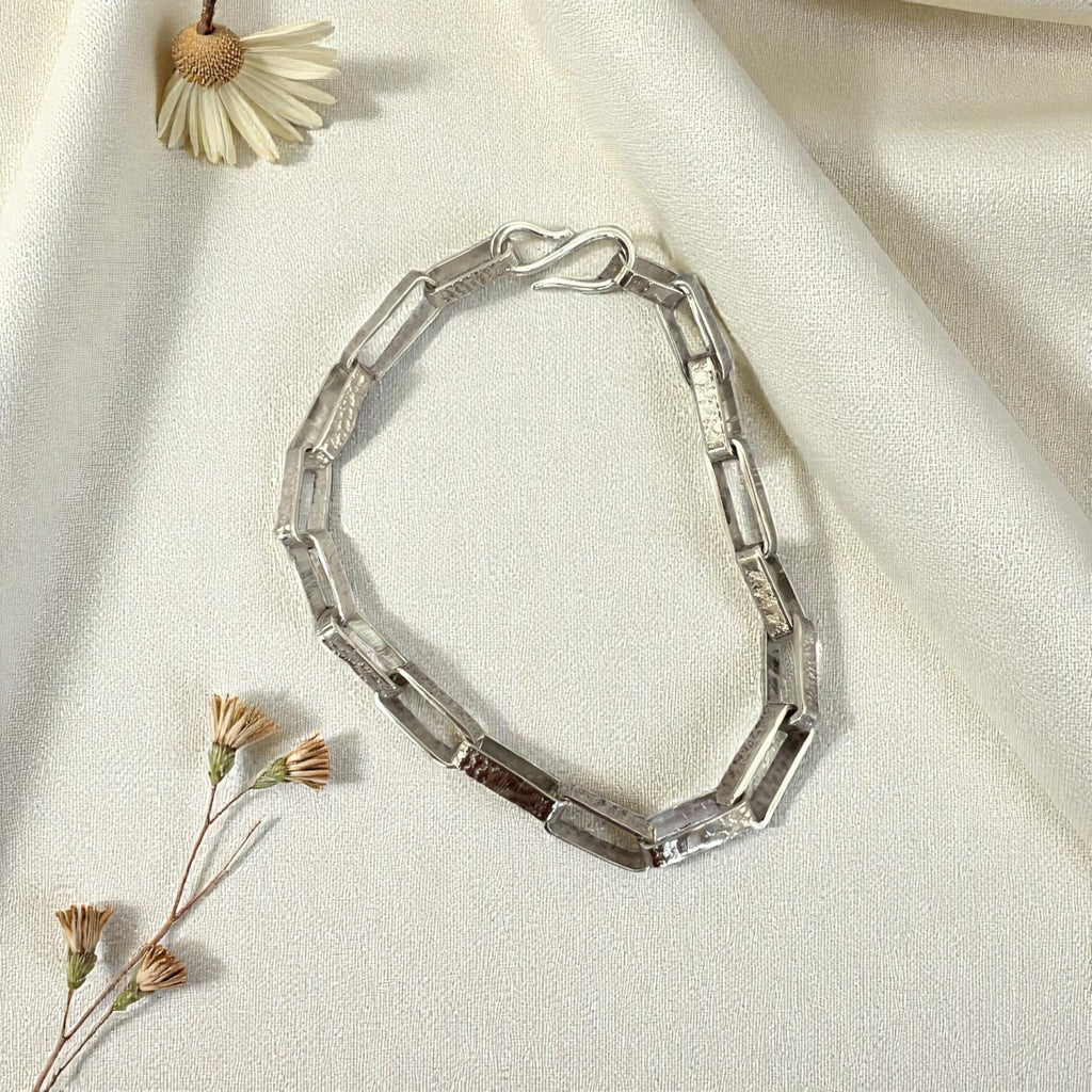 Silver bracelet on a light fabric background with dried flowers