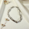Silver bracelet on a light fabric background with dried flowers