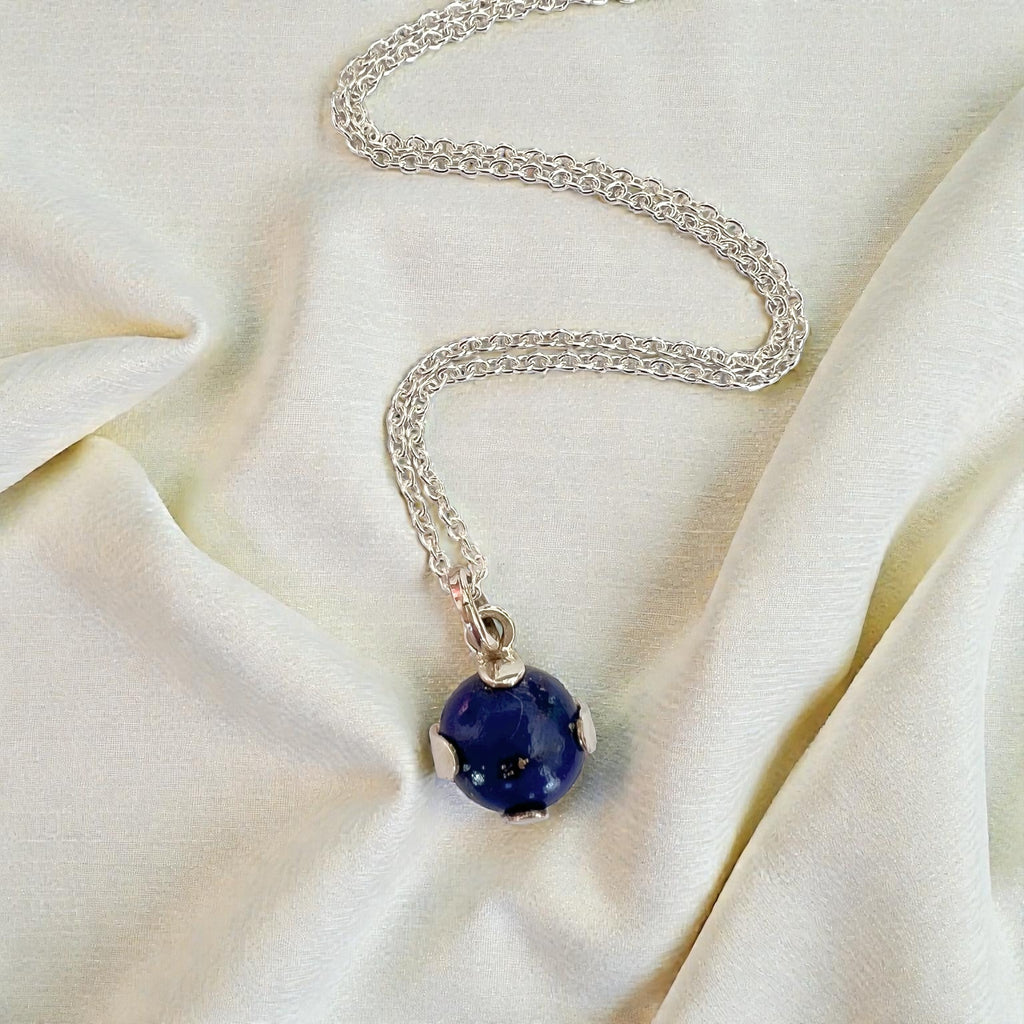 Silver necklace with a blue pendant on a beige fabric background