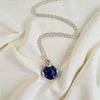 Silver necklace with a blue pendant on a beige fabric background