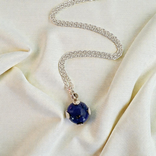 Silver necklace with a blue pendant on a beige fabric background