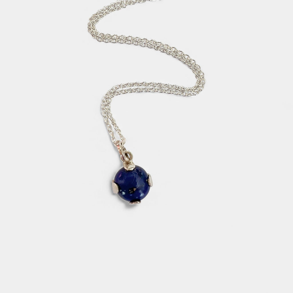 Silver necklace with a blue gemstone pendant on a white background