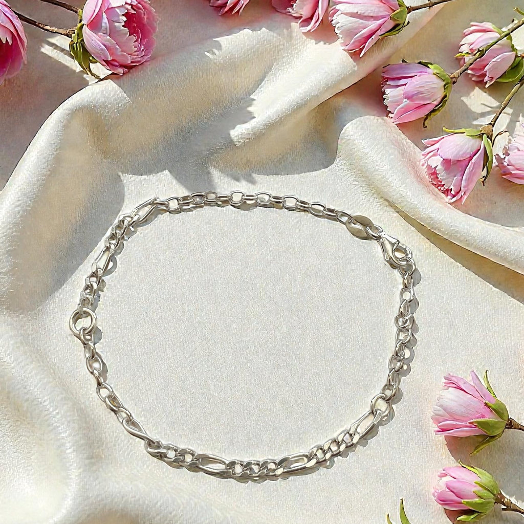 Silver bracelet on a white fabric background with pink flowers
