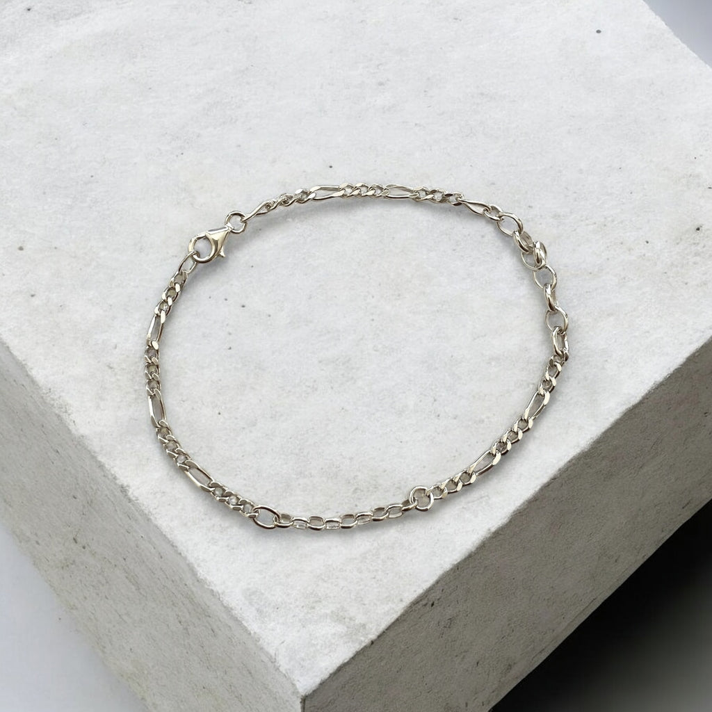 Silver chain bracelet on a light gray stone surface