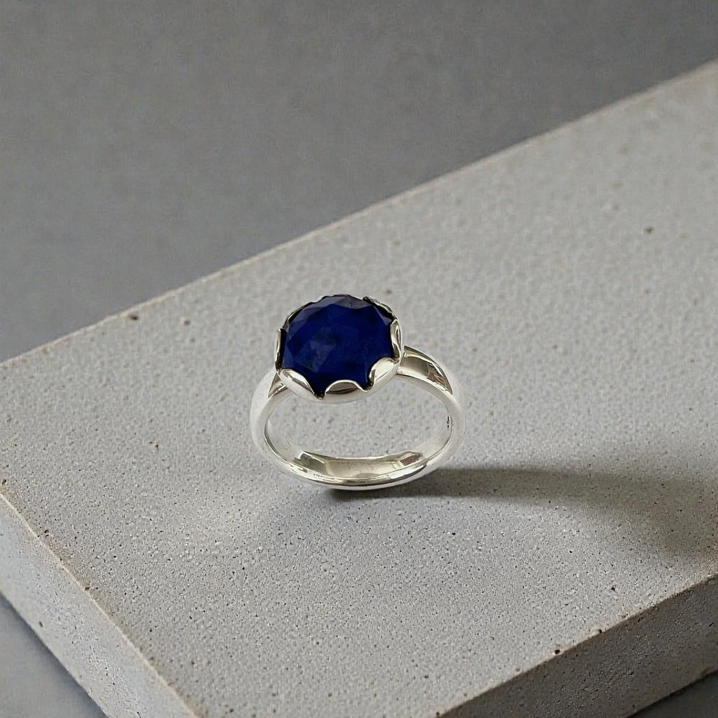 Silver ring with a blue gemstone on a gray surface