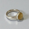 Silver ring with a yellow gemstone on a gray background
