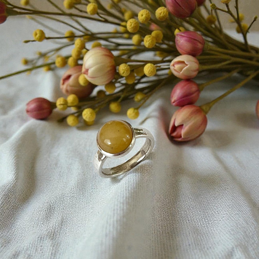 Ring with yellow stone on a white fabric background with flowers