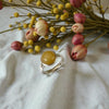 Ring with yellow stone on a white fabric background with flowers