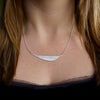 Photo of girls neck wearing Silver leaf necklace, long curved leaf with brushed texture sits sideways with on silver chain, handmade by Tania Mallow Jewellery