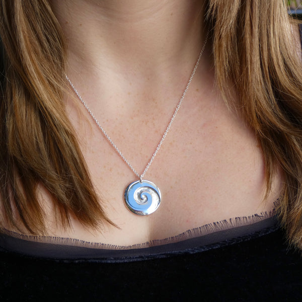 Photo of girls neck wearing silver disc pendant with Koru carved in to it, 30mm x 2.5mm, on 50cm silver chain, handmade by Tania Mallow Jewellery