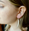 Photo of girls profile wearing Silver leaf earrings, long curved leaf shape on silver hooks, hand made by Tania Mallow Jewellery