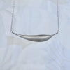 Silver leaf necklace, long curved leaf with brushed texture sits sideways with on silver chain, handmade by Tania Mallow Jewellery