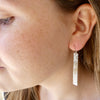 Photo of girls profile wearing Silver earrings, long rectangle shape with lace imprint, silver hooks, handmade by Tania Mallow Jewellery