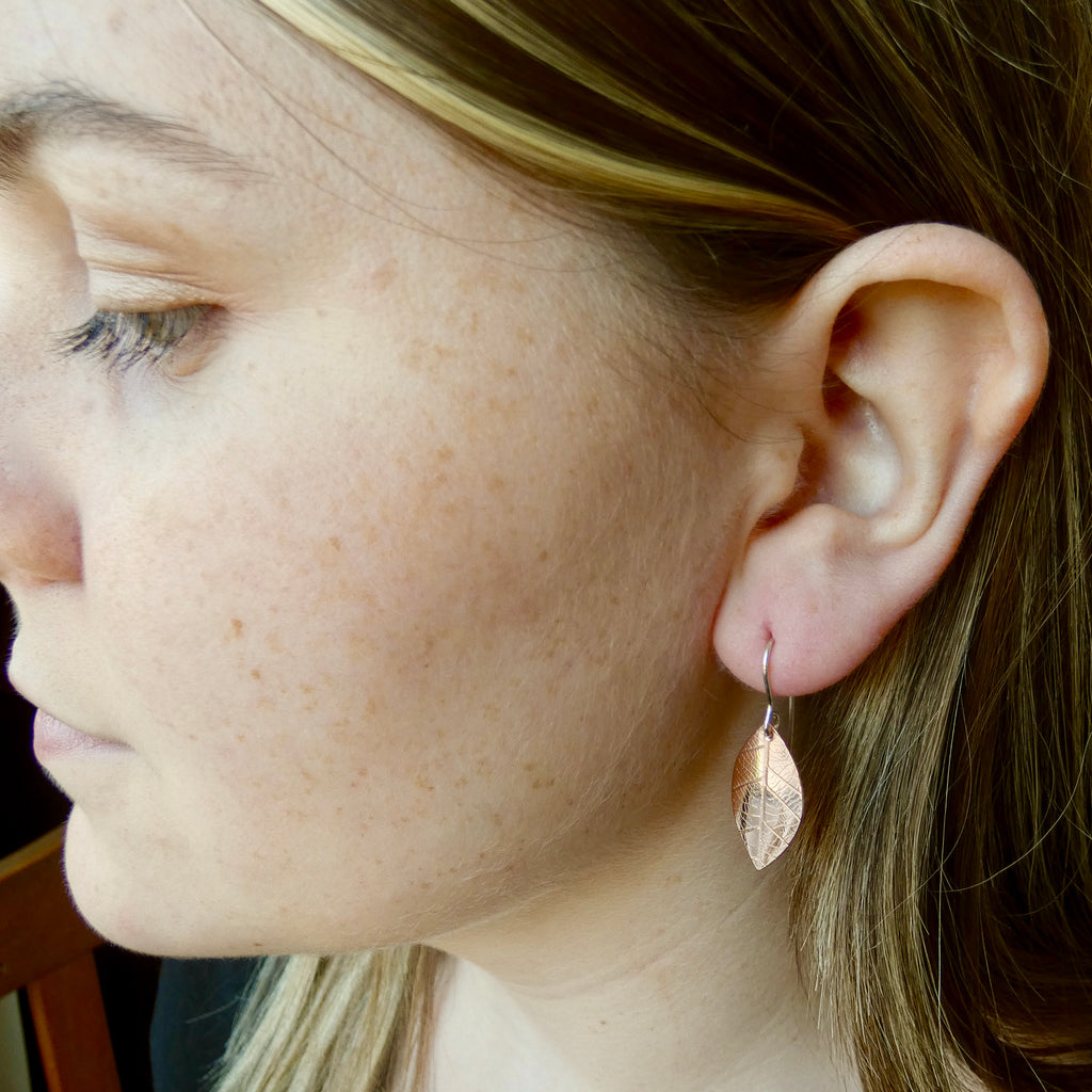 Photo of girls profile wearingCopper leaf earrings with leaf skeleton imprint, 20mm x 12mm, silver hooks, handmade by Tania Mallow Jewellery